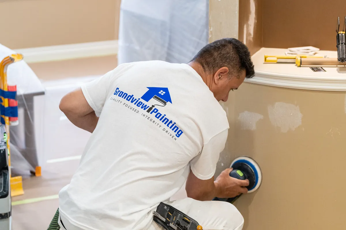 Painter sanding interior walls during prep work